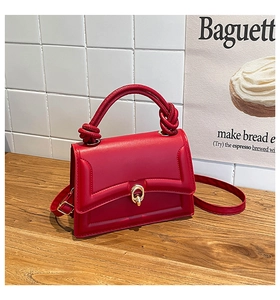 Detail of red leather crossbody bag with quilted patterns and stylish knotted handle