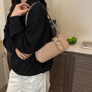 Beige minimalistische Baguette-Schultertasche mit Silberschnalle, getragen von einem Modell