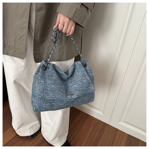 Detaillierte Makroansicht der großen blauen Denim-Tasche mit Leder- und Kettenriemen