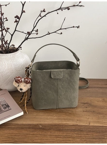 Detail der dunkelgrünen Eimer-Tasche aus Mattleder mit süßem Bärenanhänger und Riemen