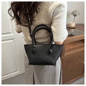 Detail view of black lychee grain bucket bag featuring a sleek trapezoidal shape