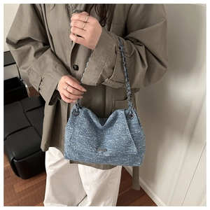 Detailansicht der blauen Tweed-Umhängetasche mit Metallkette getragen am Model