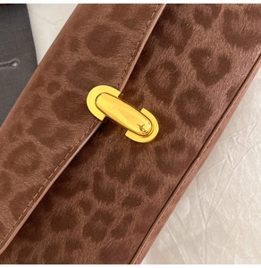 Detail of leopard print suede shoulder bag featuring a gold oval metal buckle closure