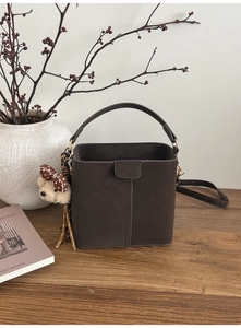 Detailansicht einer dunkelbraunen Leder-Eimertasche mit einem niedlichen Bärenanhänger