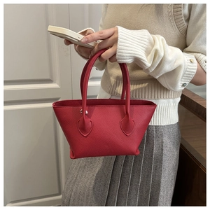 Detailed view of mini red lychee grain leather bucket bag with silver lock and ring handles