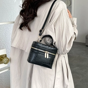 Mini black crocodile pattern bucket bag with round handle and gold zippers shown on a model