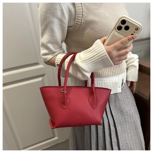 Close-up of red lychee pattern leather tote bag carried by a model in casual attire