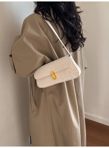 Detail of cream leopard print underarm bag with golden oval twist-lock on a model