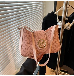 Detailed close-up of pink monogram underarm bag with gold M-logo buckle and texture