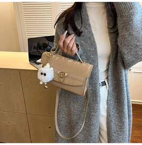 Chic beige patent leather small square bag shown with a fluffy monster charm and metal chain