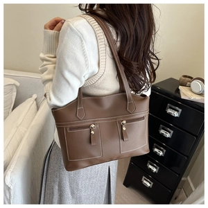 Detail of dark brown leather tote with dual front zipper pockets and contrast stitching