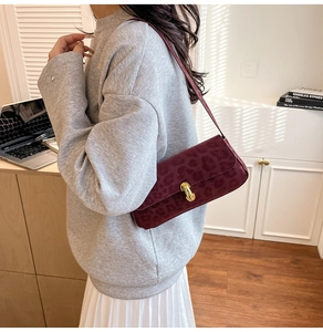 Detail of dark red leopard print shoulder bag with gold metal buckle and matte texture