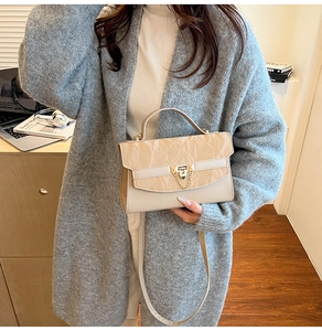 Detail view of beige trapezoid bag featuring marble texture flap and metal twist lock