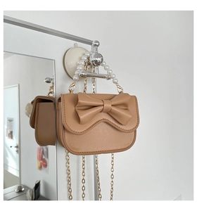 Detail of a brown bow-knot handbag with a pearl handle and gold chain shoulder strap