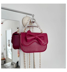 Detail of fuchsia mini crossbody bag with large bow and elegant pearl top handle