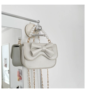 Detailed view of off-white mini bag with 3D bow, pearl handle, and gold chain strap