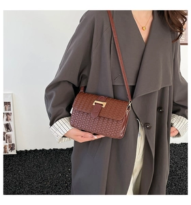 Detail of dark brown woven leather crossbody bag with a gold metal clasp and adjustable strap