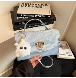 Detail of light blue crossbody bag with marble pattern flap and monster plush charm