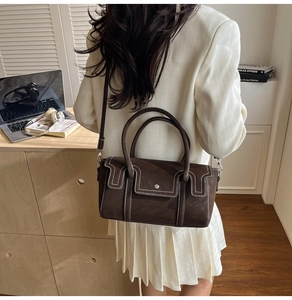 Close-up of vintage dark brown leather bag showing white contrast stitching and round buckle
