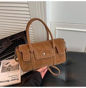 Detail of brown faux leather handbag with white contrast stitching and silver hardware