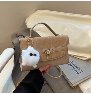 Detail of crossbody bag featuring marble pattern flap and golden buckle with plush charm