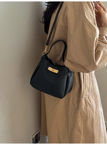 Detail of black pebbled leather bucket bag with gold twist lock and crossbody strap