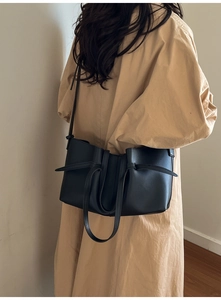Detail view of black matte leather tote bag featuring unique side drawstring accents