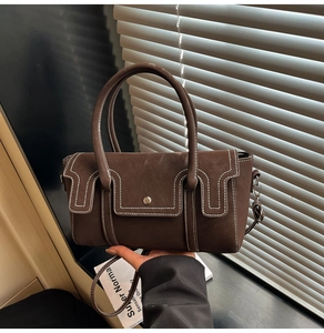 Detail view of brown vintage satchel with white contrast stitching and magnetic metal buckle