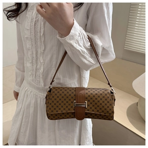 Dettaglio borsa a spalla retrò marrone con monogramma e fibbia argentata su abito bianco