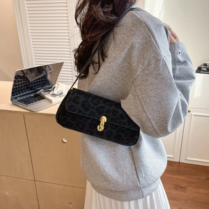 Fashionable black leopard print baguette bag with gold lock buckle on a female model