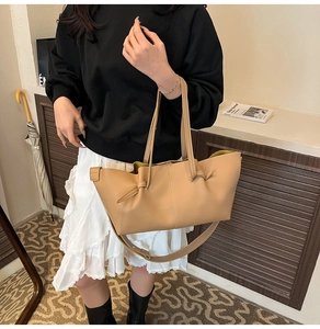 Detail view of beige tote bag with unique knot decor and matte leather texture on model