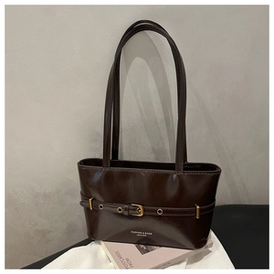 Detail of a chocolate brown tote bag showing glossy leather texture and gold belt buckle
