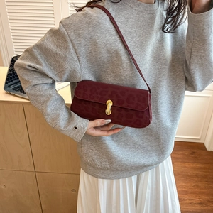 Elegant burgundy leopard print underarm bag with gold oval lock in a cozy room setting