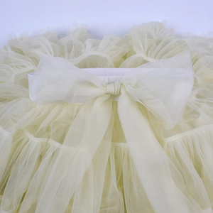 Close-up of layered beige tulle tutu skirt featuring a decorative large mesh bow at the waist