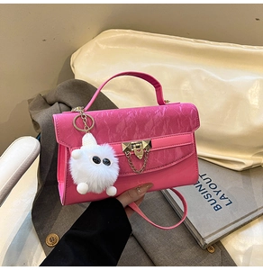 Pink patent leather crossbody bag featuring gold hardware and a fluffy monster charm