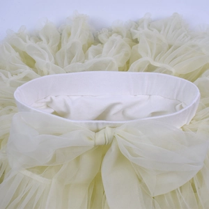 Detail view of elastic waistband and large tulle bow on creamy yellow tutu skirt