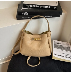 Close-up of beige lychee pattern leather handbag featuring a golden rectangular twist lock