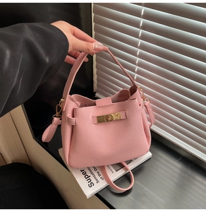 Detail of pink lychee grain bucket bag featuring a gold metal twist lock and wide handle