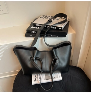 Detail of black matte tote bag featuring a knotted handle and adjustable shoulder strap