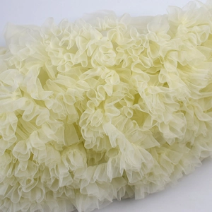Detailed close-up of soft beige ruffled tulle layers and fine mesh fabric texture
