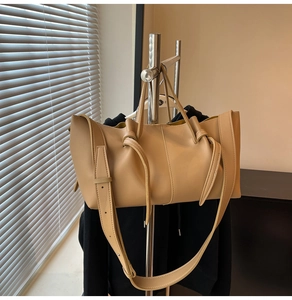 Detail view of khaki matte leather tote bag featuring a knotted handle and adjustable strap