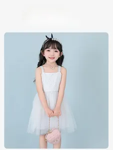 Detail of girls' white lace tulle dress with pearl accessories and heart bag