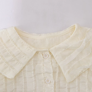 Close-up of beige girl shirt featuring a Peter Pan collar with plissé pleated fabric details