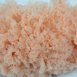 Macro detail of multi-layered pleated peach tulle fabric on a fluffy tutu skirt