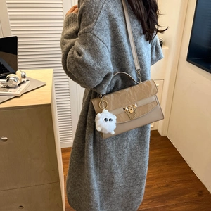 Chic khaki crossbody flap bag with gold chain and plush charm shown from a side view
