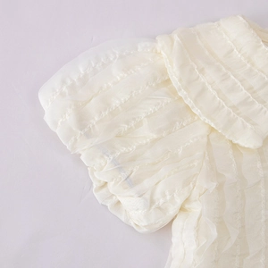 Detailed view of layered off-white pleated fabric with elegant ruffles and fine texture