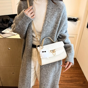 Cream white crossbody flap bag with gold chain and plush ball worn by a model