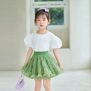 Detail of girls' white puff sleeve top with pearl necklace and green layered tutu skirt