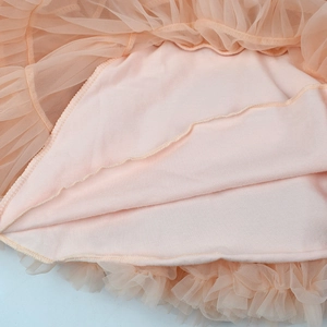 Detail of light orange multi-layer tutu skirt showing soft cotton lining and neat stitching