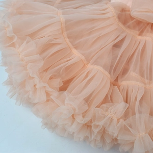 Close-up detail of multi-layered soft apricot pink tulle tutu skirt with ruffled edges